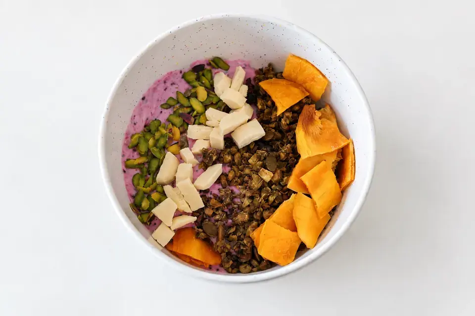Matcha granola over pink dragon-fruit yogurt with pistachios, white chocolate, and dried mango