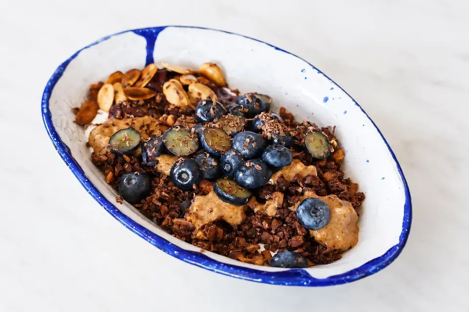 Chocolate granola bowl topped with blueberries, almonds, and almond butter