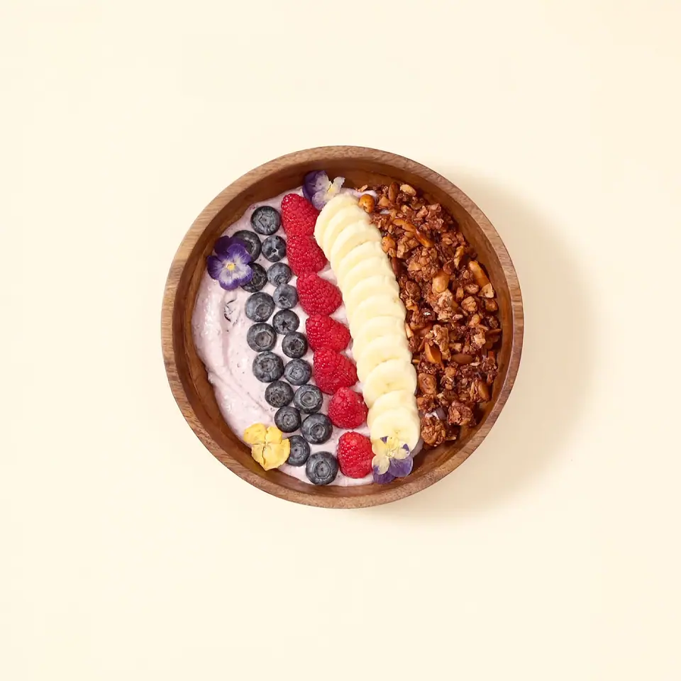 Blueberry lavender coconut granola bowl with rows of berries and banana slices