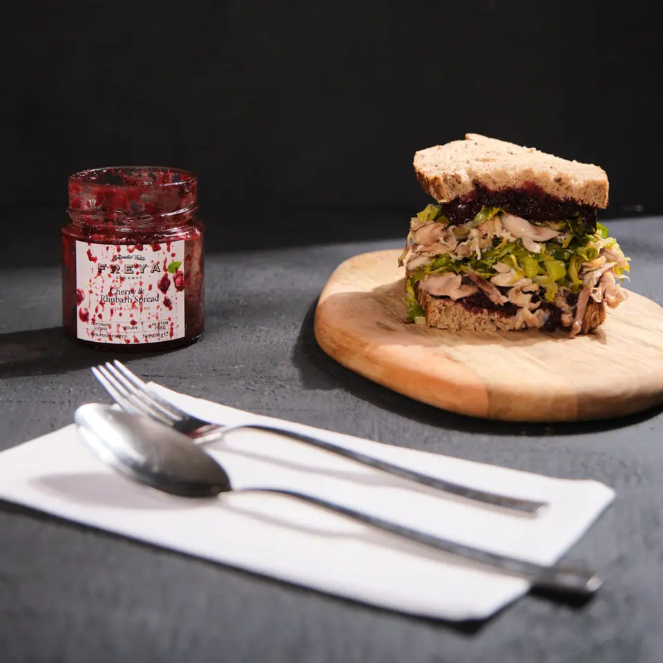 Cherry and rhubarb chicken sandwich stacked on a wooden board