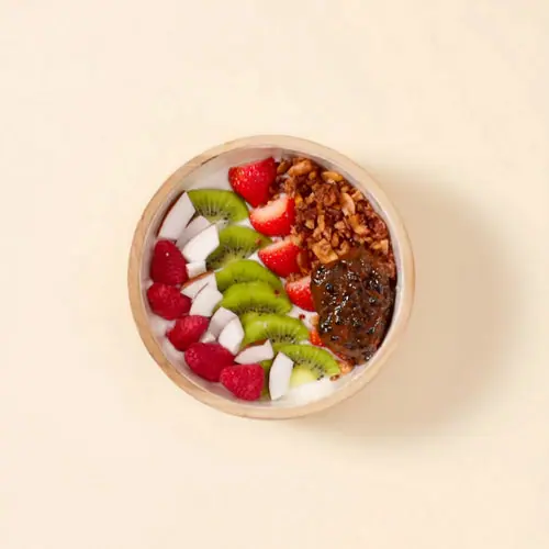 Coconut granola bowl with coconut milk, strawberries, kiwi, and coconut flakes