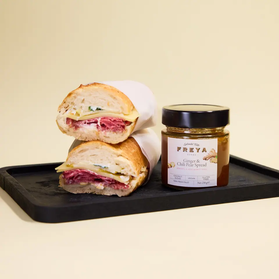 Ginger-spiced pear baguette sandwich halves on a black serving board