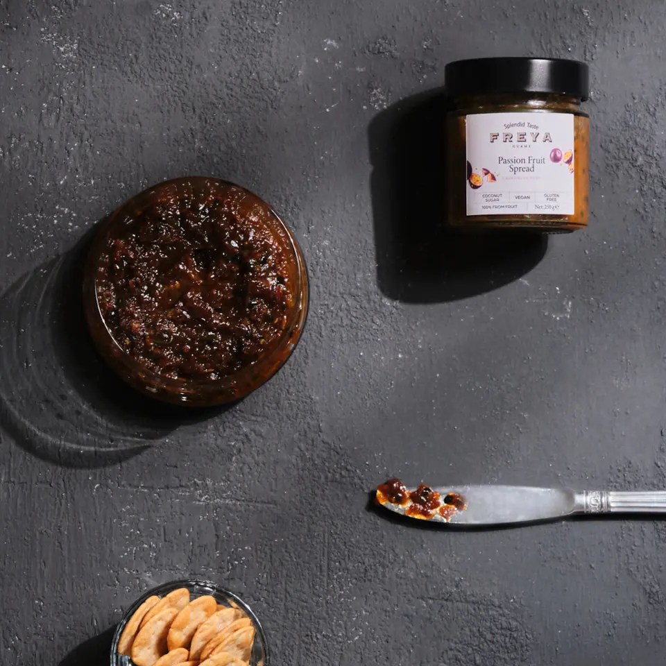 Dark passion fruit chutney in a small bowl with a serving spoon