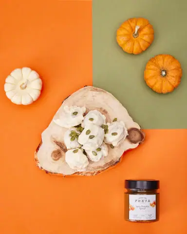 White-coated spiced pumpkin truffles on a platter with small decorative pumpkins